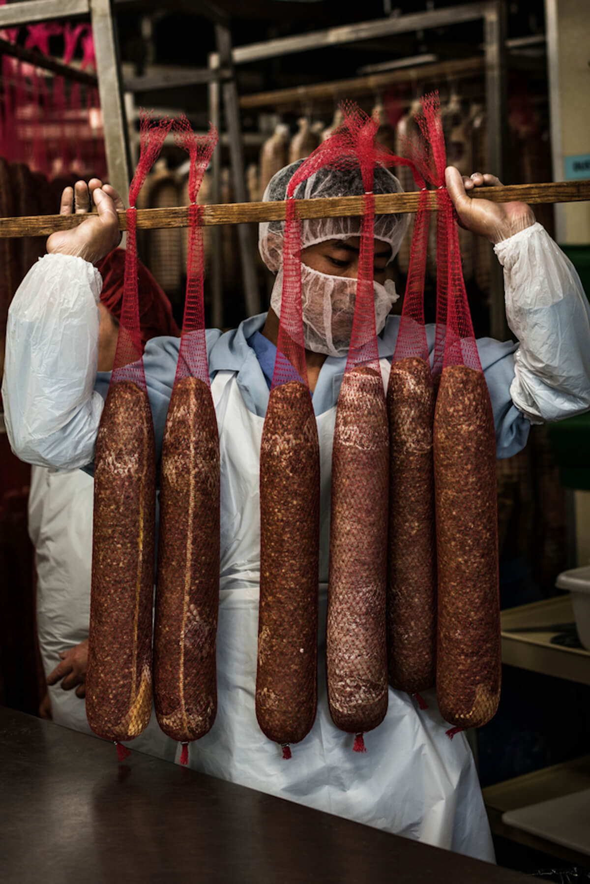 volpi employee holding a salami rack 